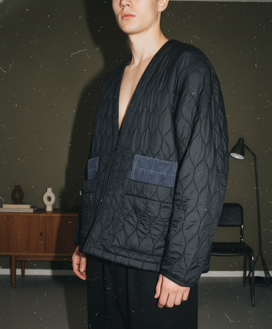 UJOHのウェーブキルトライナージャケット。異素材のパッチポケットが特徴的なノーカラーデザイン。